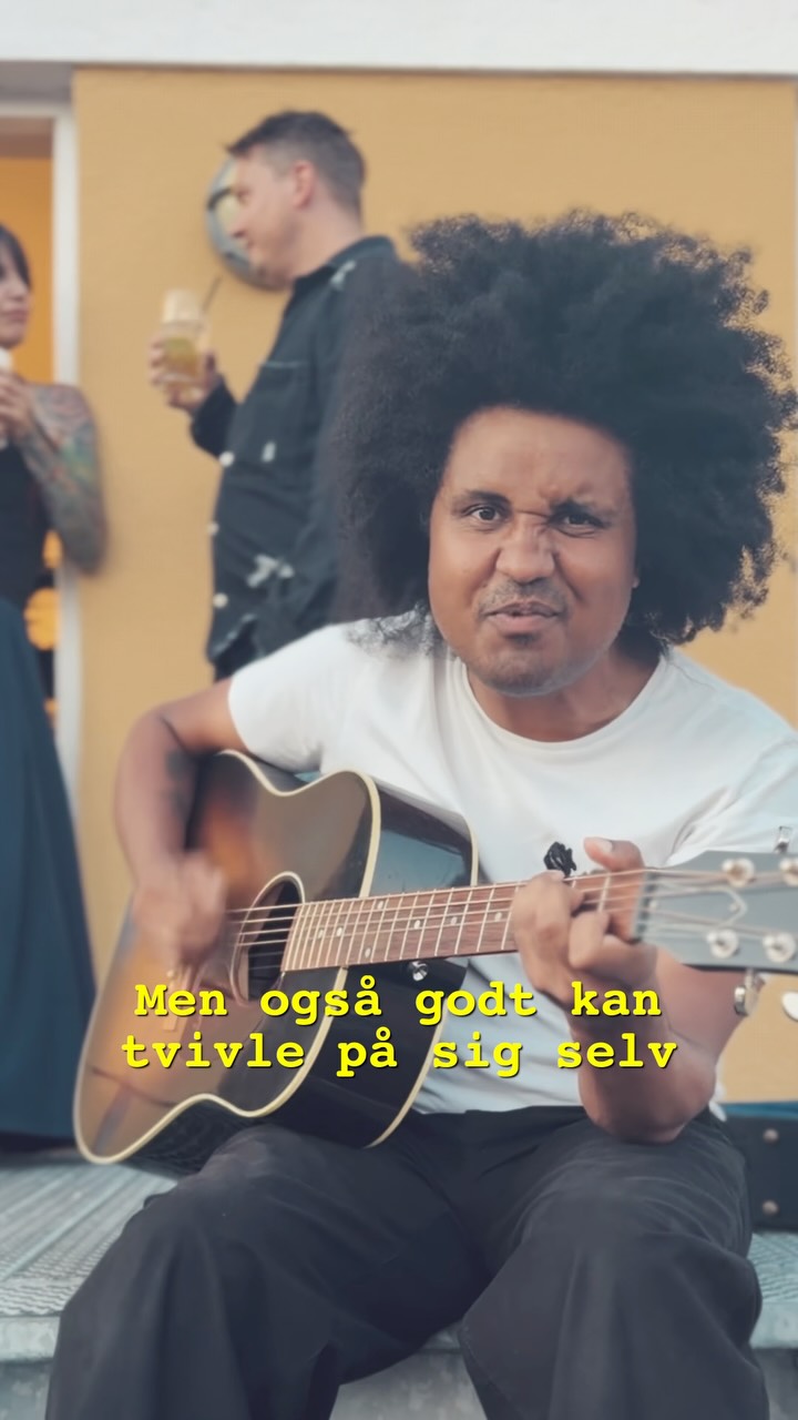 Thomas Buttenschøn sidder med sin guitar på en trappe.